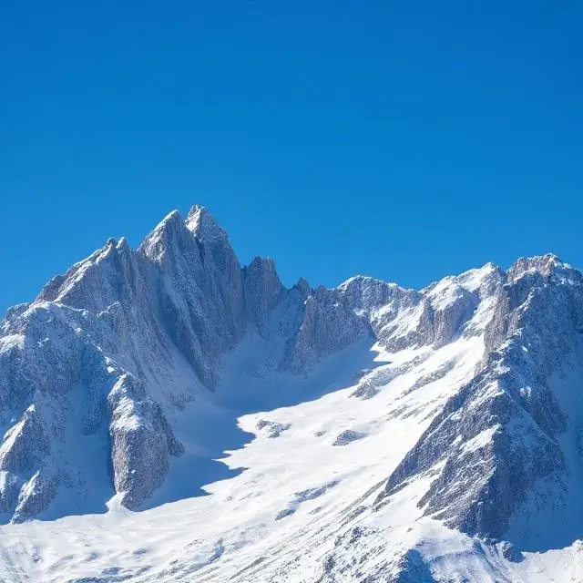 Jagged, snowy peaks of the Alps under a clear blue sky.